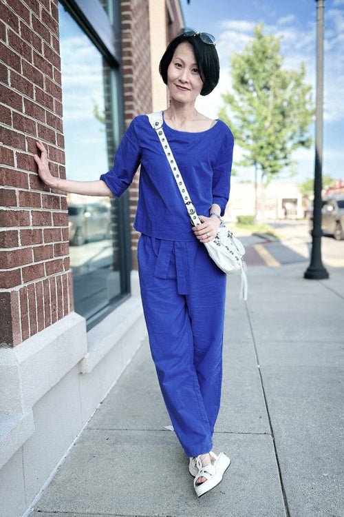 Woman wearing relaxed cotton-linen monochrome capsule longline top and wide-leg pants in blue on city sidewalk
