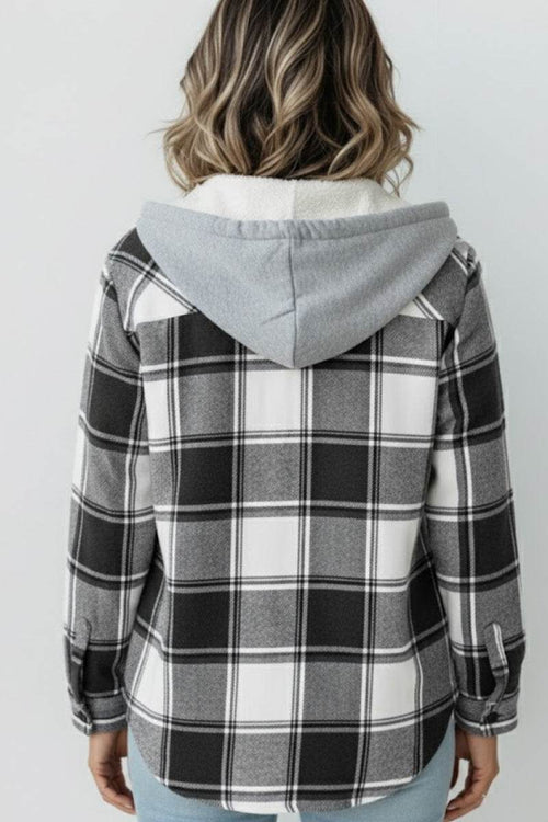 Back view of a woman wearing a black and white Highland Plaid Shacket with a grey hood and fleece lining.