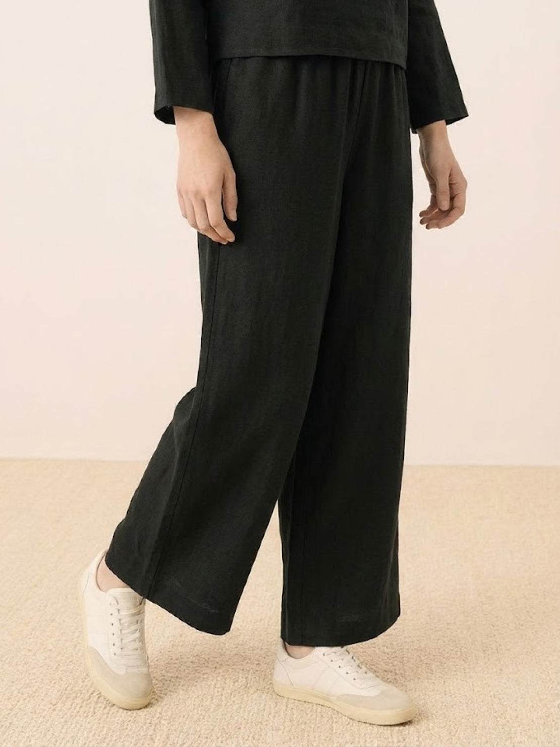 woman wearing loose solid color two-piece set with round neck top and wide-leg pants standing outdoors