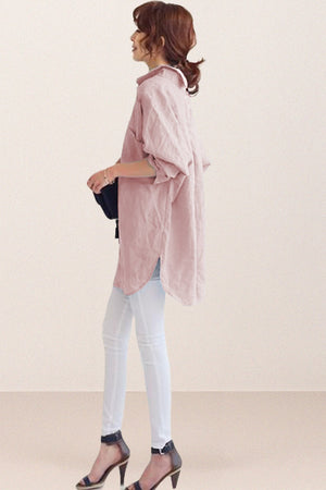 woman wearing oversized linen shirt in sun-washed pink with rolled sleeves and white pants