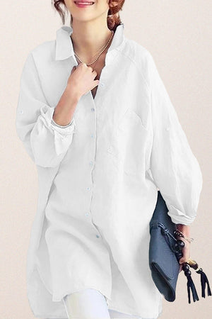 White oversized linen shirt with relaxed fit and button details worn by woman holding a clutch