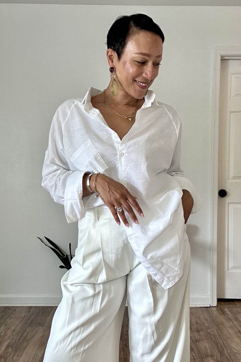 Woman wearing white oversized linen shirt with relaxed fit and white trousers indoors
