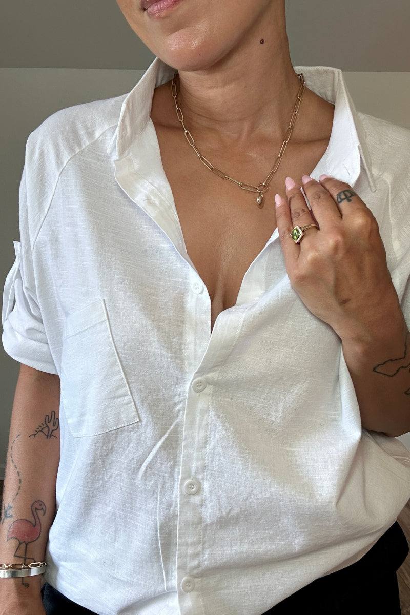 Woman wearing oversized white linen shirt with rolled-up sleeves and a front pocket