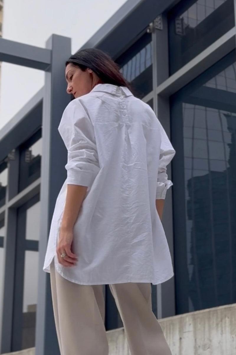 woman wearing oversized linen shirt in white with back gathers and buttons outdoors
