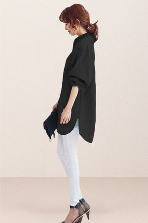Woman wearing oversized black linen shirt with rolled sleeves and white pants, side view, minimalist background