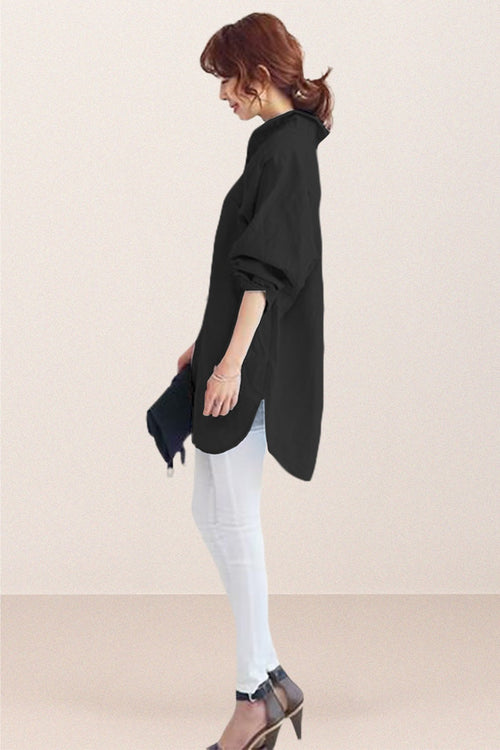 Woman wearing oversized black linen shirt with rolled sleeves and white pants, side view, minimalist background