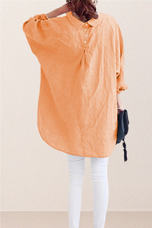 Back view of oversized linen shirt in soft orange with relaxed fit and button details worn with white pants