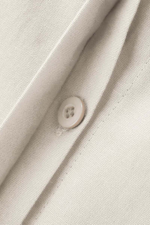 Close-up of beige oversized 100% cotton shirt fabric with button detail