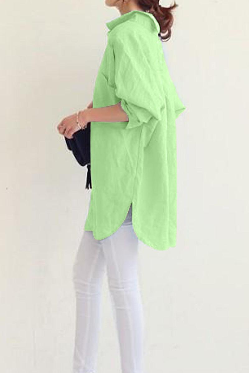 woman wearing oversized light green linen shirt with rolled-up sleeves and white pants side view