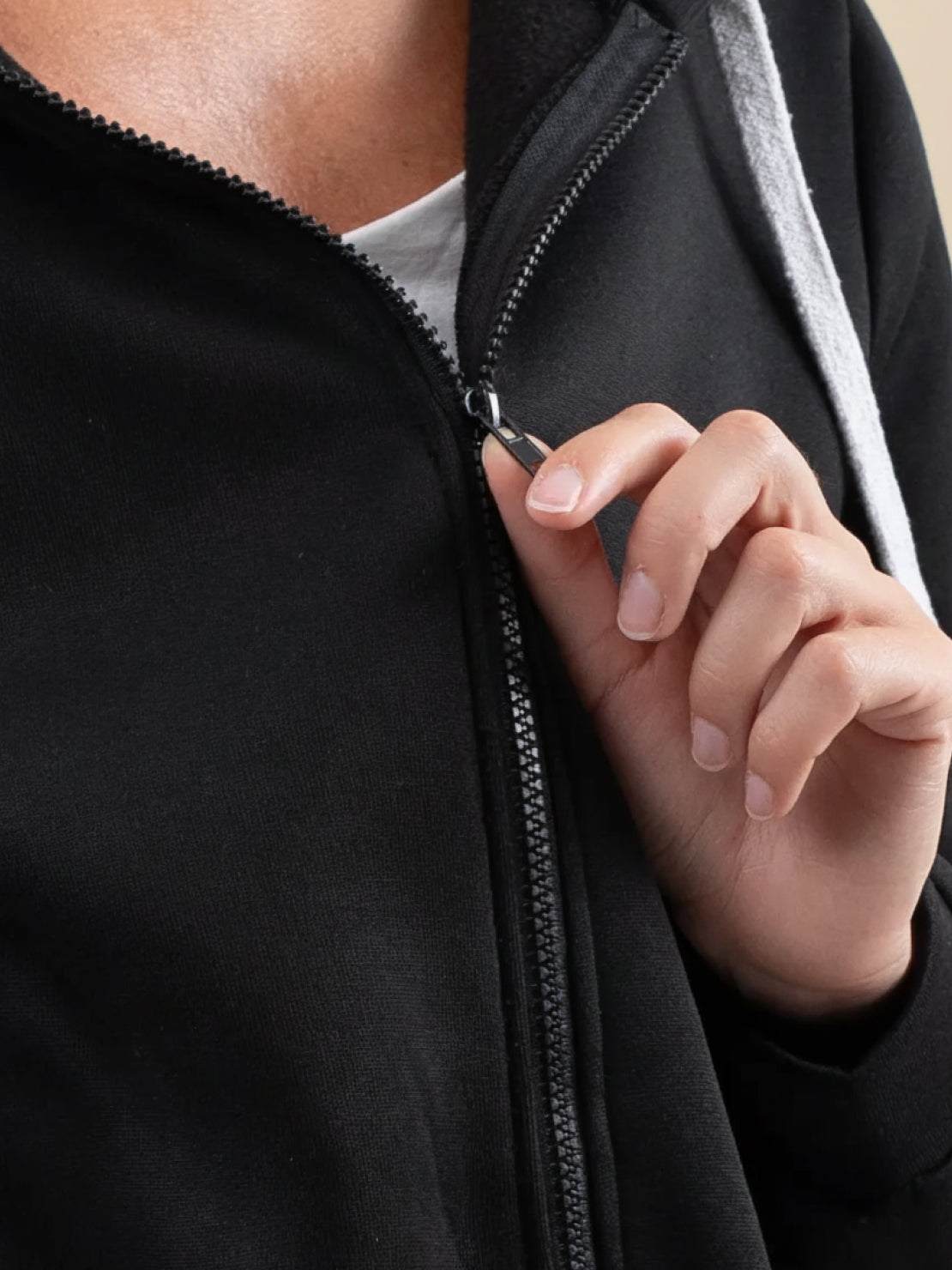 Close-up of hand zipping black oversized long zip sweatshirt hoodie with fleece lining and drawstring hood