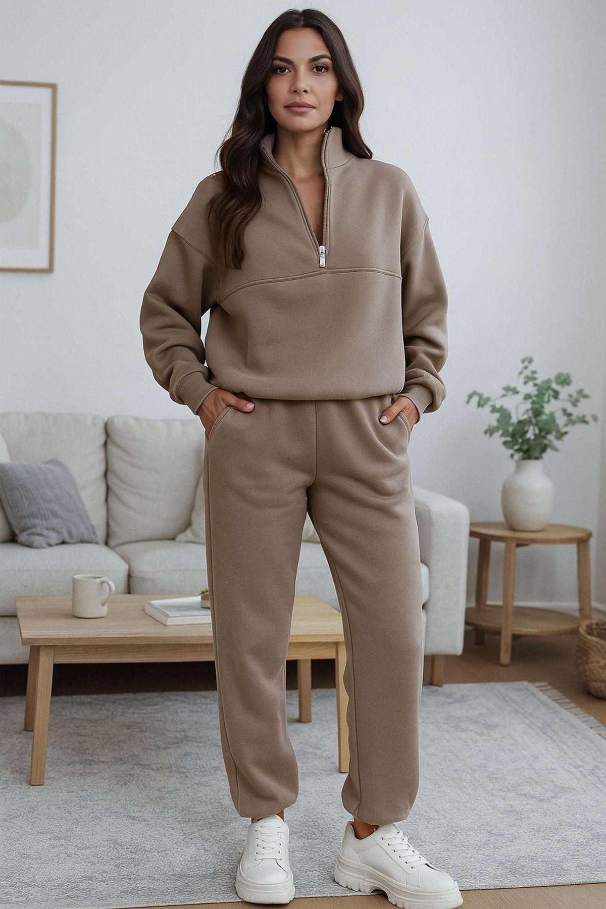 Woman wearing neutral toned cotton blend tracksuit with zip neckline and stretch waistband in a modern living room