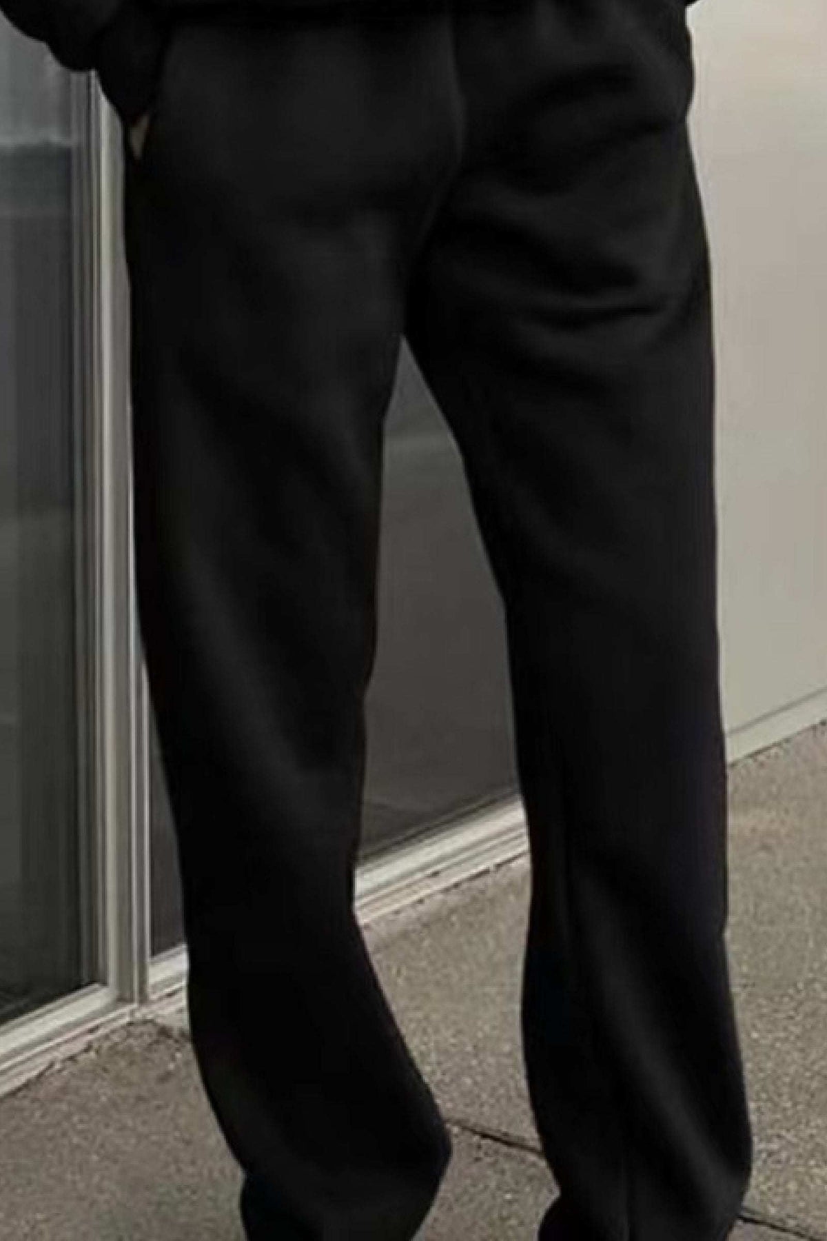 Black cotton blend tracksuit pants with a relaxed fit and stretch waistband worn outdoors