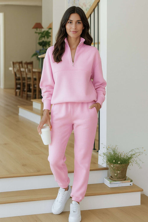 Woman wearing pink cotton blend tracksuit with zip neckline and white sneakers indoors