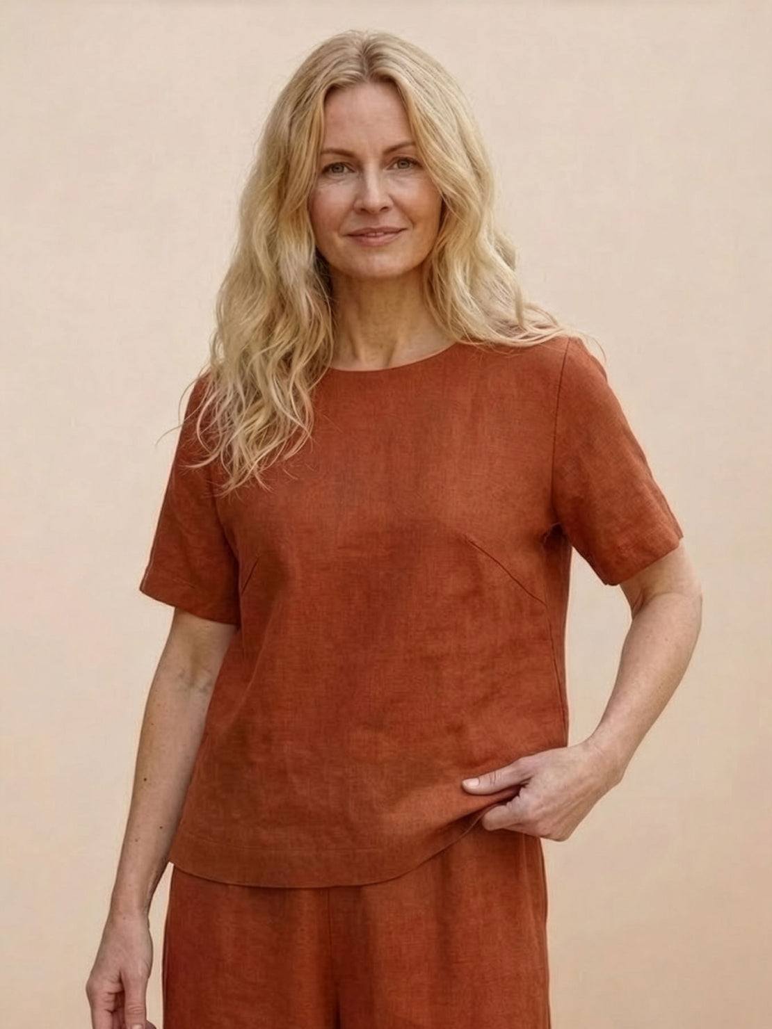 woman wearing rust-colored loose fit co-ord set with short sleeves and wide-leg pants against neutral background