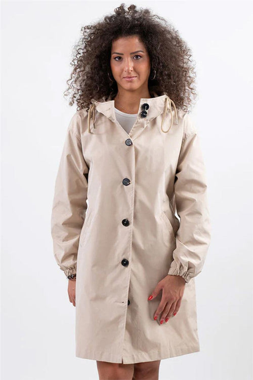 Woman wearing beige Rain Couture Windbreaker oversized water-resistant jacket with hood and button closure
