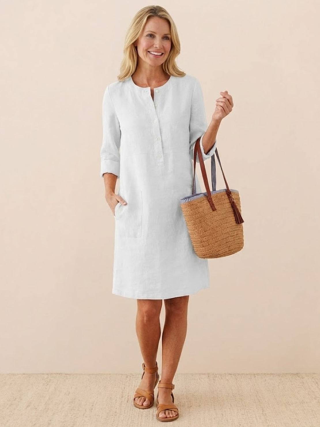 woman wearing white cotton dress with 3/4 sleeves carrying a straw handbag