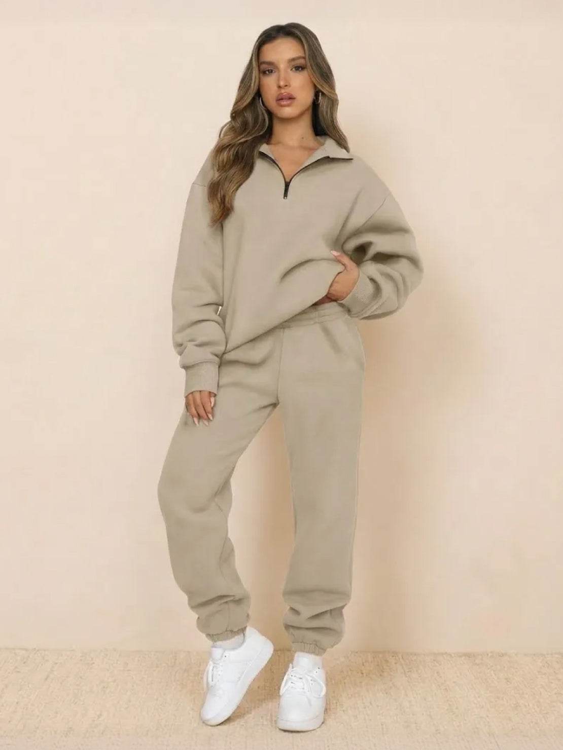 Woman wearing beige ultra-soft and comfy co-ord tracksuit set with white sneakers against plain background