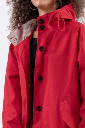 Red oversized Rain Couture Windbreaker with button closure and adjustable hood on female model