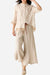 Woman wearing 100% cotton linen Tuscany two-piece set with sheer embroidered top and wide-leg trousers in beige tones.