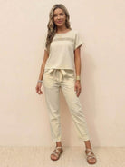 Woman wearing beige 100% cotton total comfort two-piece travel set with short sleeve top and drawstring pants.