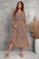 Woman wearing a brown floral Bloom Wrap Midi Dress with long trumpet sleeves and an A-line silhouette