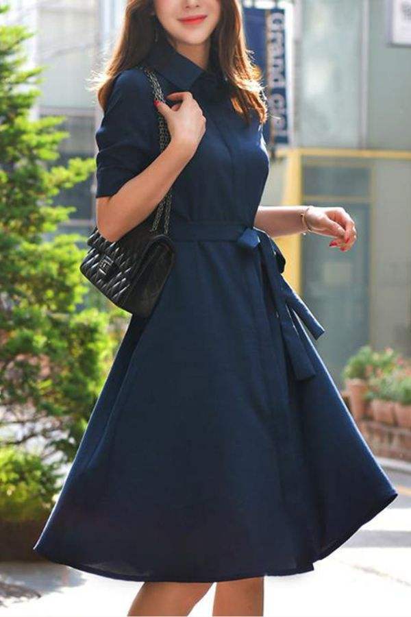 Woman wearing navy radiance belted shirt dress with a classic collar and detachable belt, styled for a casual outdoor setting.