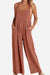 Woman wearing rust-colored Free-Flow Wide Leg Overalls with adjustable straps and a loose fit.