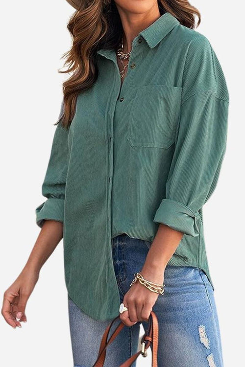 Woman wearing green sleek suede oversized button-down shirt with rolled-up sleeves and blue ripped jeans