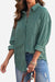 Woman wearing green sleek suede oversized button-down shirt with rolled-up sleeves and blue ripped jeans