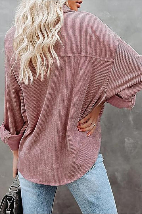 Back view of a woman wearing a sleek suede oversized button-down shirt in dusty rose paired with light blue jeans