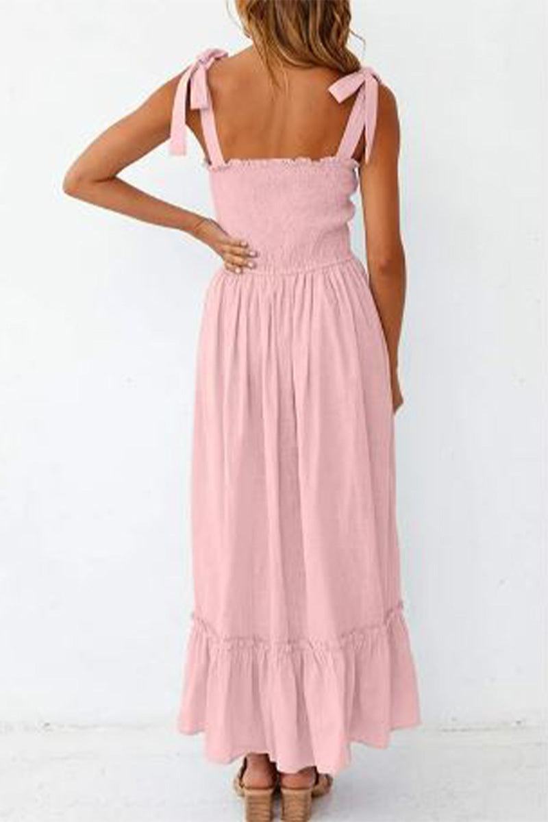 Back view of a woman wearing a pink Sunkissed Spaghetti Boho Dress with adjustable tie-up ribbon straps and a flowy, high-waist silhouette