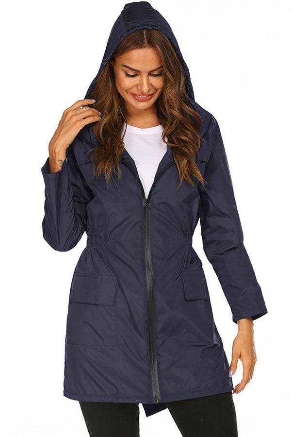 Woman wearing navy blue outdoor and travel hooded raincoat windbreaker jacket with front zipper and pockets