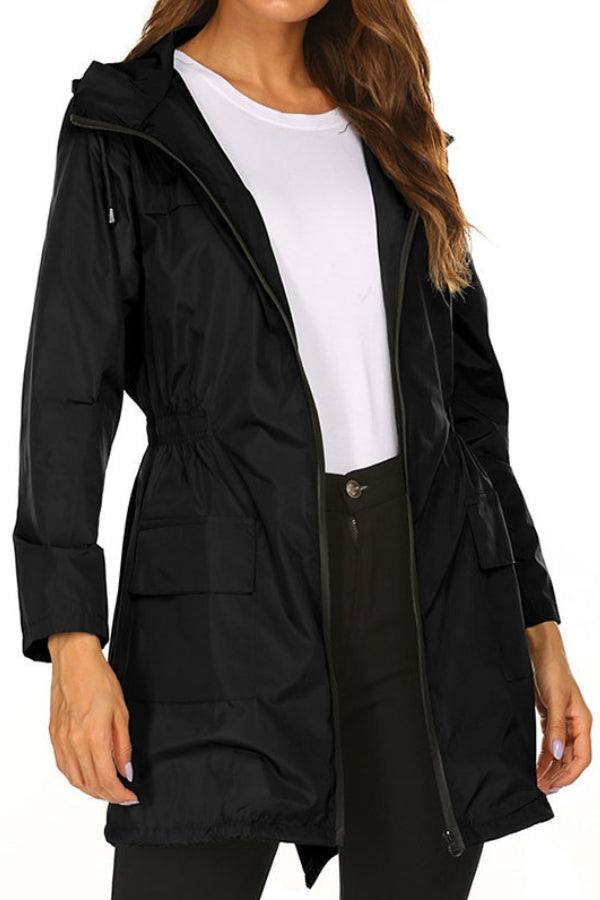 Woman wearing black outdoor and travel hooded raincoat windbreaker jacket with front pockets and zipper closure