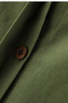 Close-up of olive green relaxed shirt and trousers set fabric with brown button detail