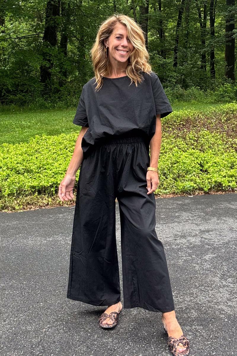 Woman wearing black loose fit co-ord set with wide-leg pants and relaxed short sleeve top outdoors