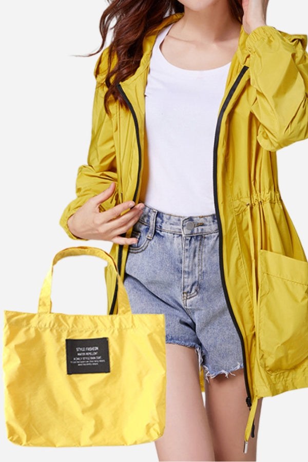 Travel ready outdoor yellow raincoat windbreaker with adjustable waist and matching packable bag.