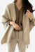 Woman wearing relaxed flowy open front knitwear cardigan in beige over taupe top and light pants