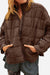 Brown lightweight puffer travel jacket with quilted design, front zipper, and pockets, styled for casual wear.