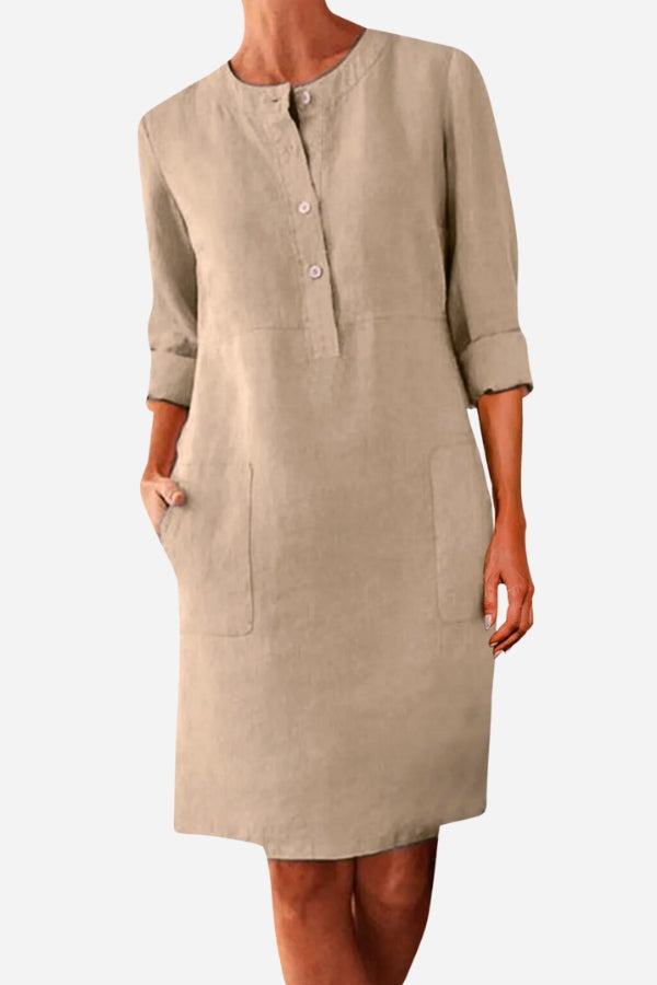 Beige cotton dress with half-button front, rolled ¾ sleeves, knee-length, and practical pockets, suitable for summer and casual wear.