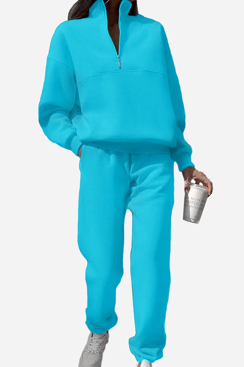 Woman wearing bright blue cotton-blended two-piece tracksuit with high collar and zipper holding a cup.