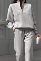 Light gray cotton-blended two-piece tracksuit with high collar and deep zipper, modeled outdoors holding a coffee cup.