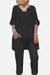 Black asymmetrical two-piece trouser set with loose top and tapered pants, featuring rolled-up sleeves and a relaxed fit.