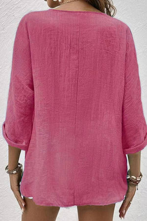 Back view of a pink breezy button front tunic with rolled sleeves on a woman