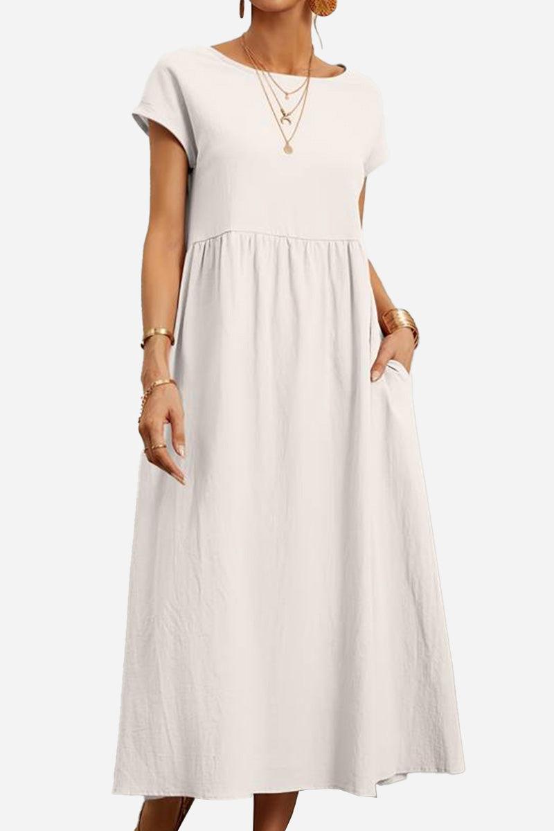 Woman wearing a white capped-sleeve voluminous pleated midi dress with pockets and layered necklaces
