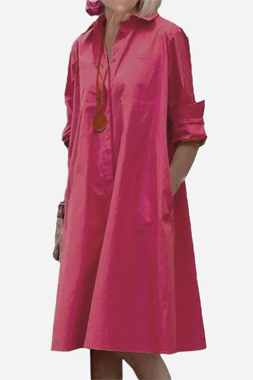 Pink long shirt-style dress with collar and rolled-up sleeves, loose fit, and pockets.