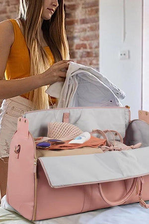 Pink no-wrinkle foldable travel bag open with clothes and personal items inside