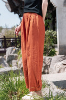 Woman wearing loose fit orange ramie linen cotton pants outdoors near traditional building