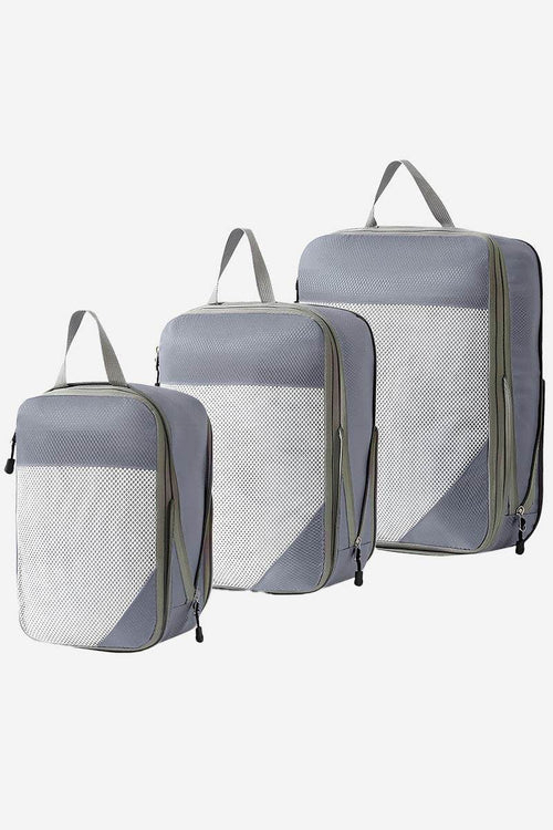 Set of three grey space-saving compression packing organizers with handles and mesh fronts for travel and suitcase organization