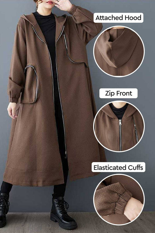 ZipLine oversized long coat in brown with attached hood, zip front, elasticated cuffs, and large zippered pockets, styled for versatile travel wear.