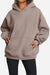 Woman wearing oversized fleece-lined hoodie in taupe with kangaroo pocket and relaxed fit